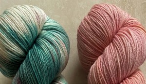 two skeins of yarn with aqua varigated tones on the left and peachy colored on the right